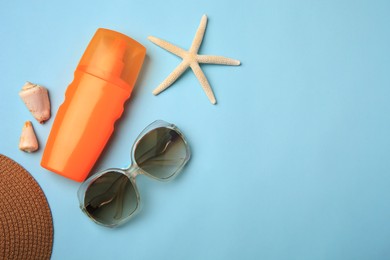 Flat lay composition with bottle of sunscreen on light blue background. Space for text