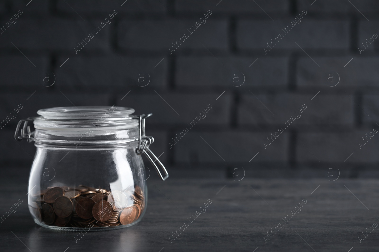 Photo of Glass jar with coins on grey table. Space for text