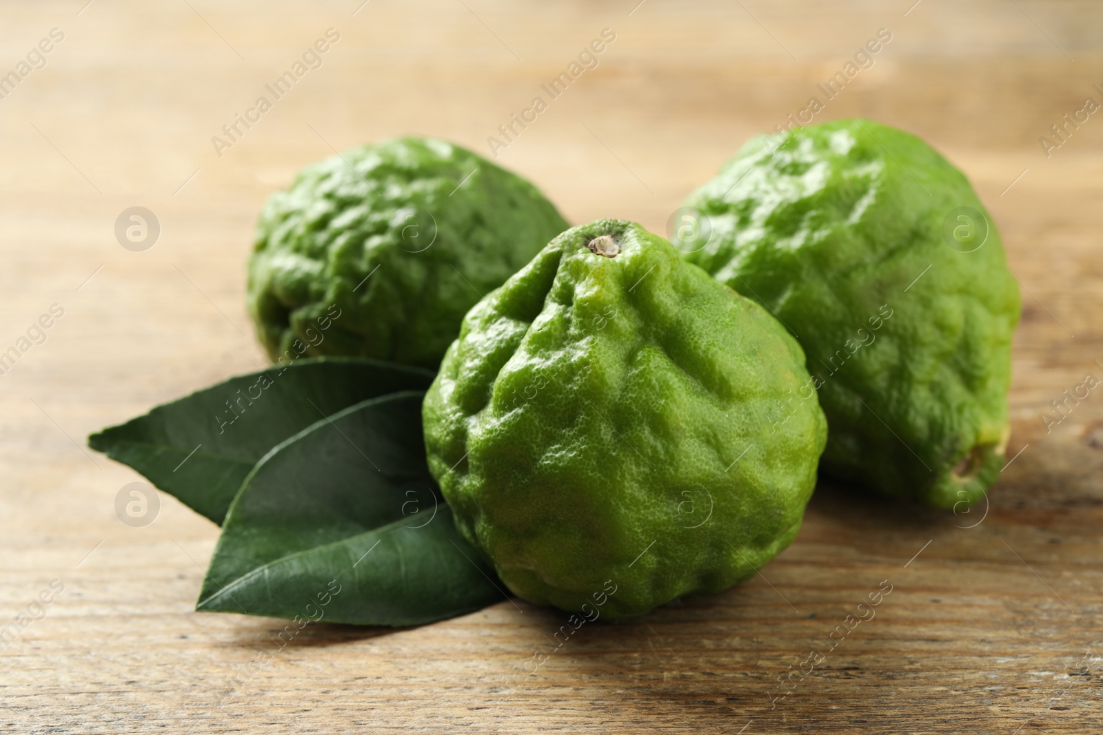 Photo of Fresh ripe bergamot fruits and leaves on wooden table