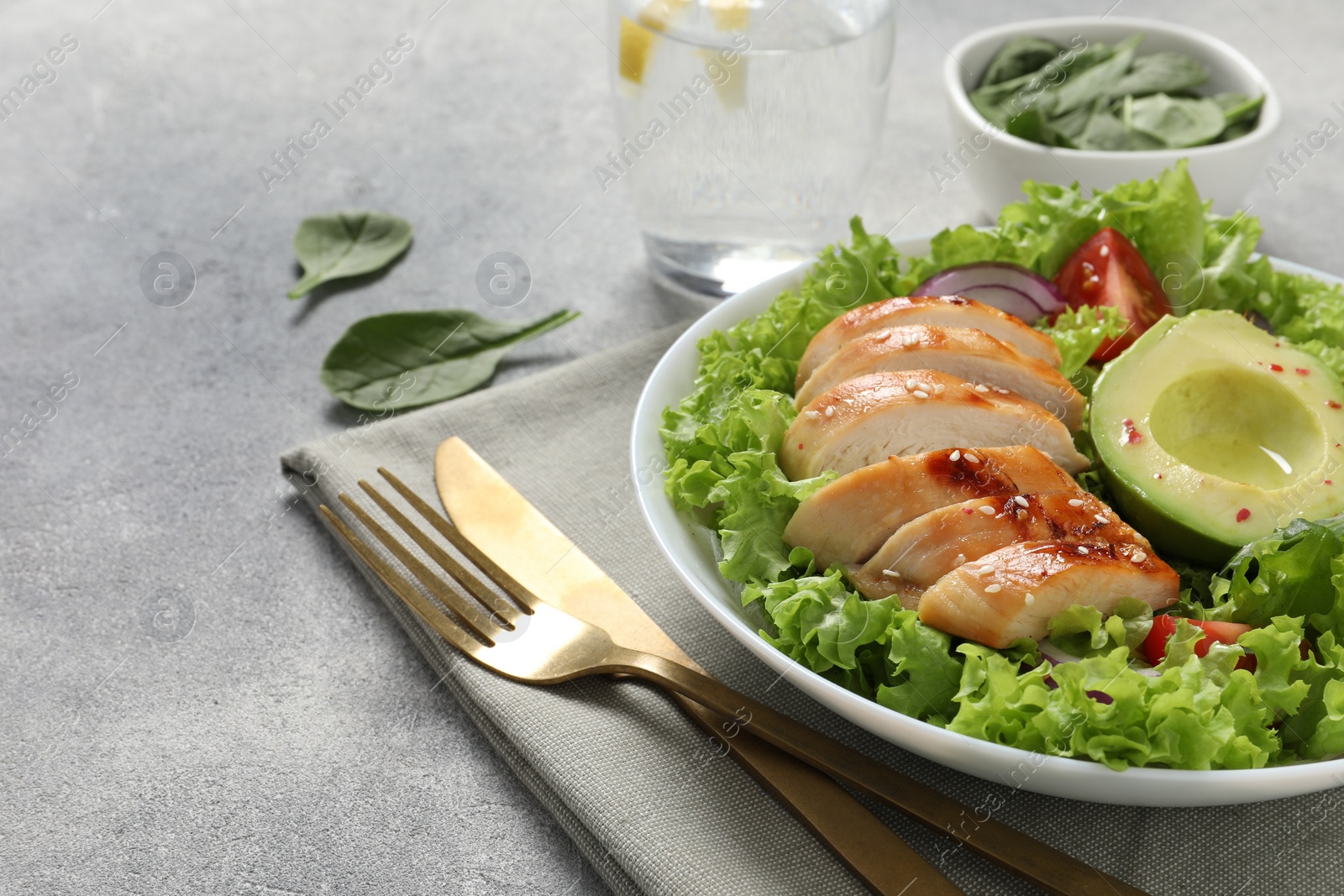 Photo of Delicious salad with chicken, avocado and vegetables served on light grey table, closeup. Space for text