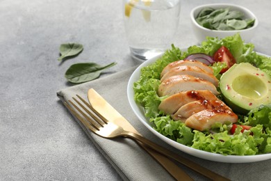 Delicious salad with chicken, avocado and vegetables served on light grey table, closeup. Space for text