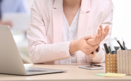 Photo of Young woman suffering from wrist pain in office