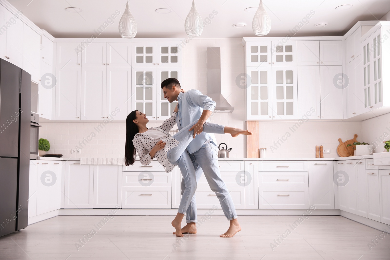 Photo of Happy couple dancing barefoot in kitchen. Floor heating system
