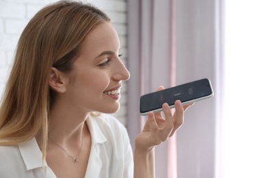 Young woman using voice search on smartphone indoors