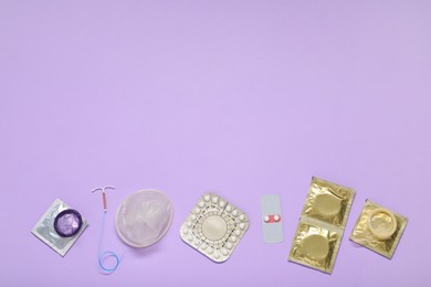 Photo of Contraceptive pills, condoms and intrauterine device on lilac background, flat lay and space for text. Different birth control methods