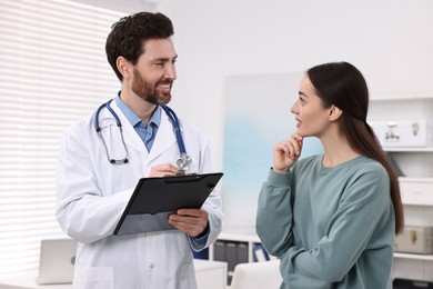 Doctor with clipboard consulting patient during appointment in clinic