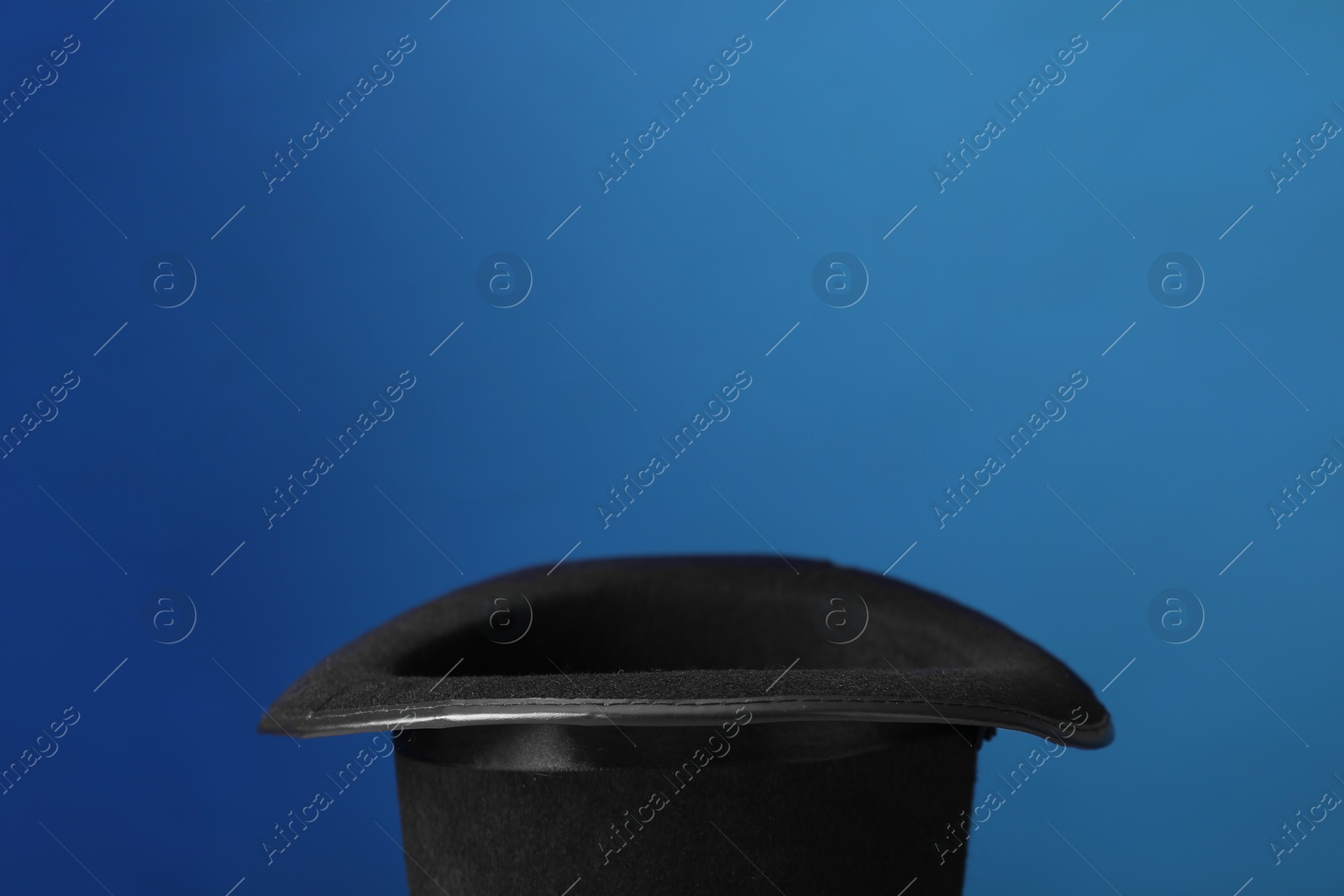 Photo of Magician's hat on blue background, space for text