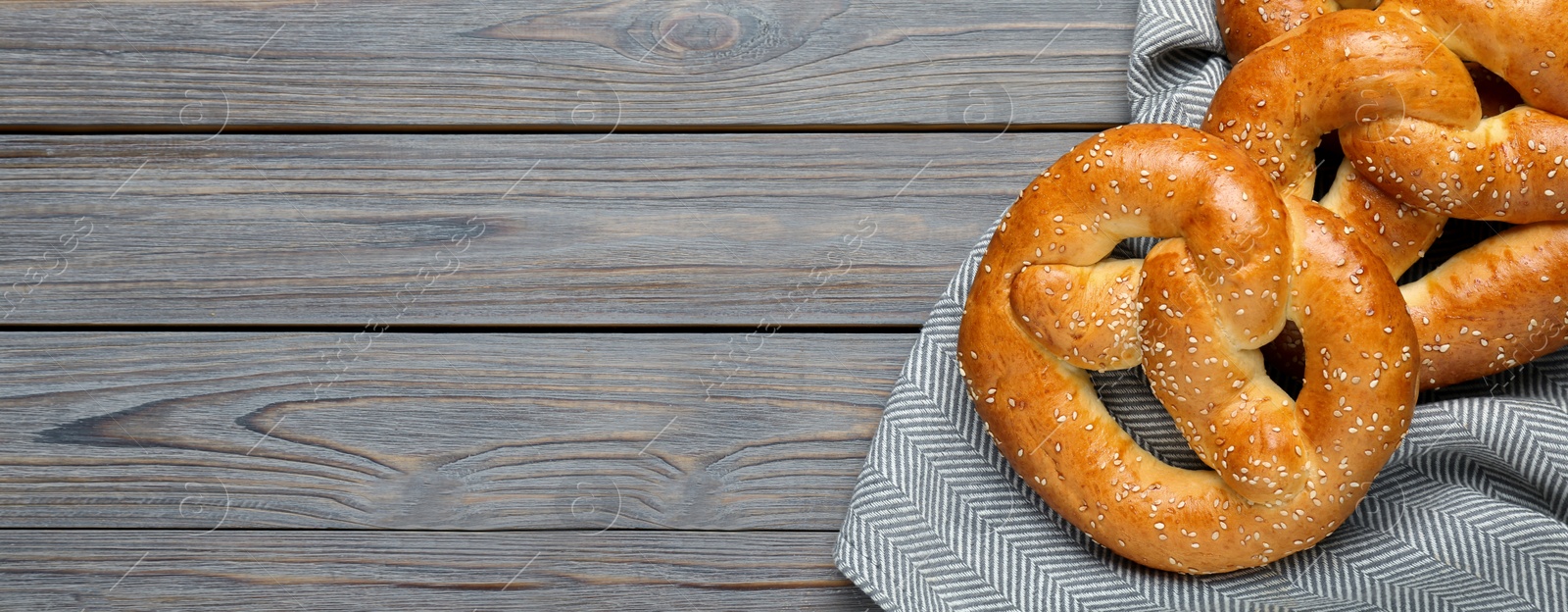 Image of Tasty freshly baked pretzels on wooden table, top view with space for text. Banner design