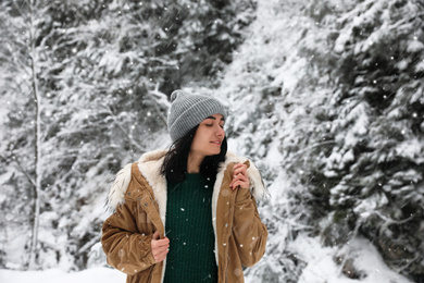 Photo of Young woman wearing warm clothes outdoors on snowy day. Winter vacation