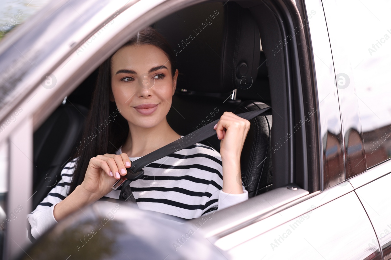 Photo of Woman fastening safety seat belt inside modern car