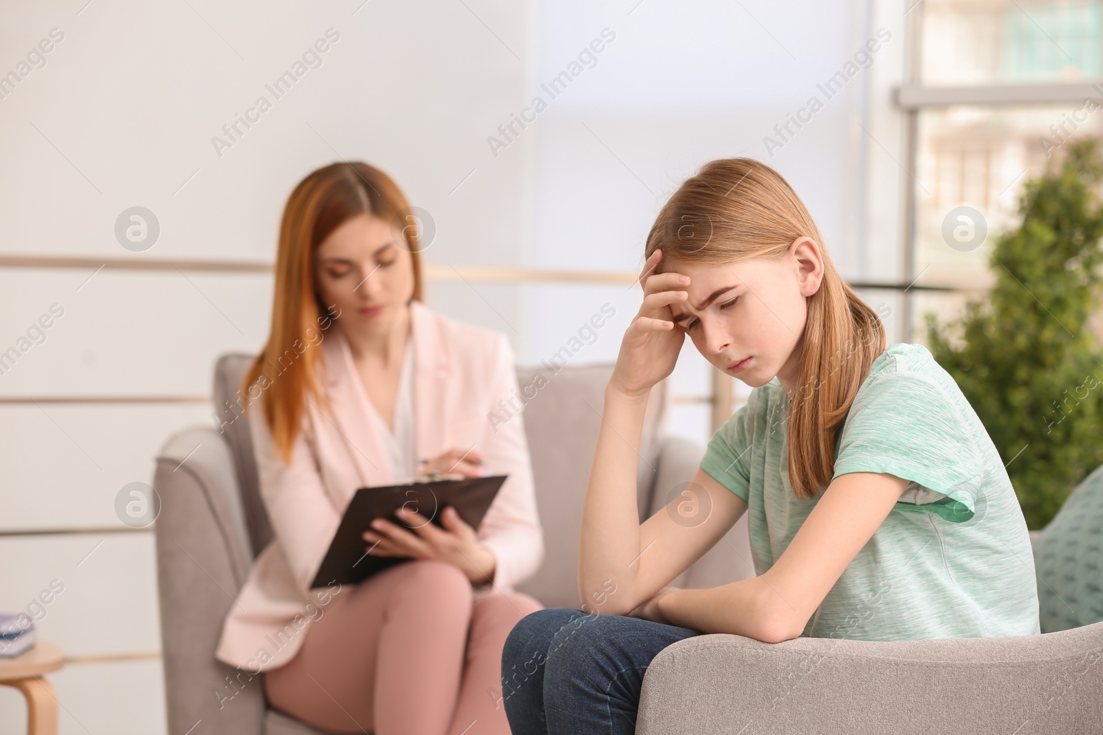 Photo of Young female psychologist working with teenage girl in office