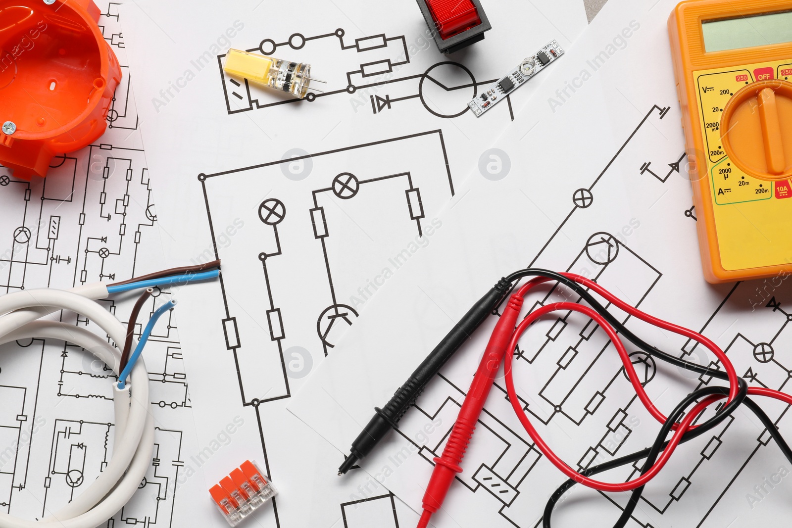 Photo of Digital multimeter and other electrician's equipment on wiring diagrams, flat lay