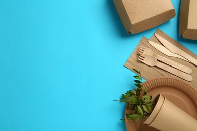 Flat lay of paper and wooden tableware with green twigs on turquoise background, space for text. Eco friendly lifestyle