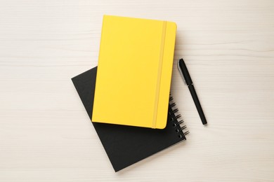 Photo of Notebooks and pen on white wooden table, flat lay