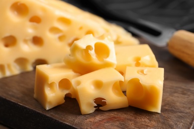 Photo of Pieces of delicious cheese on wooden board, closeup