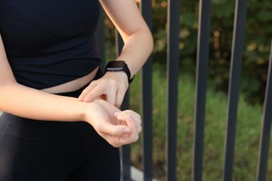 Photo of Woman checking pulse after training outdoors, closeup. Space for text