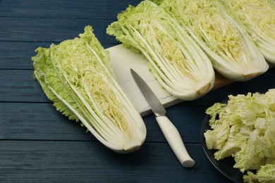 Photo of Cut fresh ripe Chinese cabbages on blue wooden table