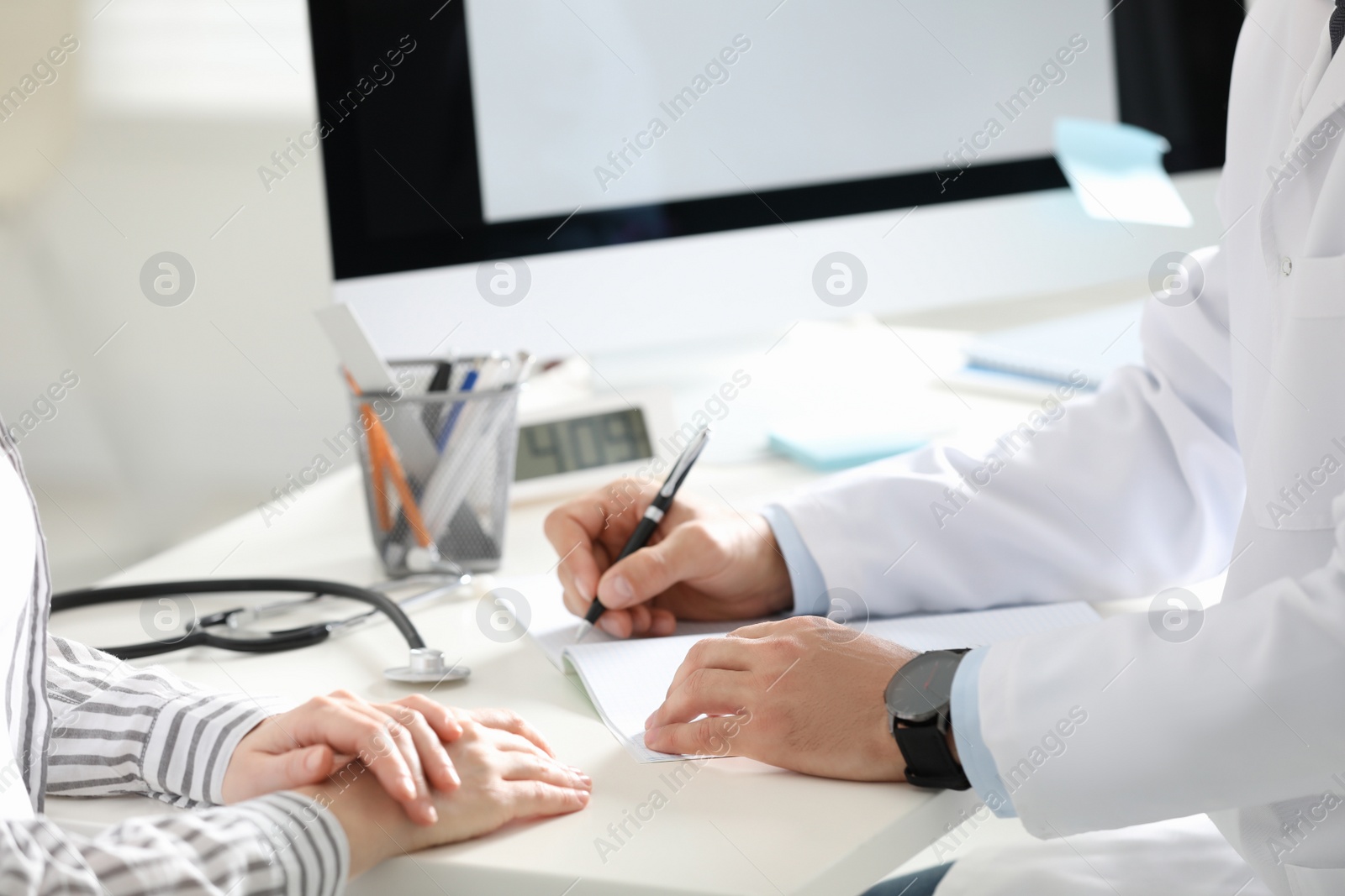 Photo of Doctor working with patient at desk in office, closeup