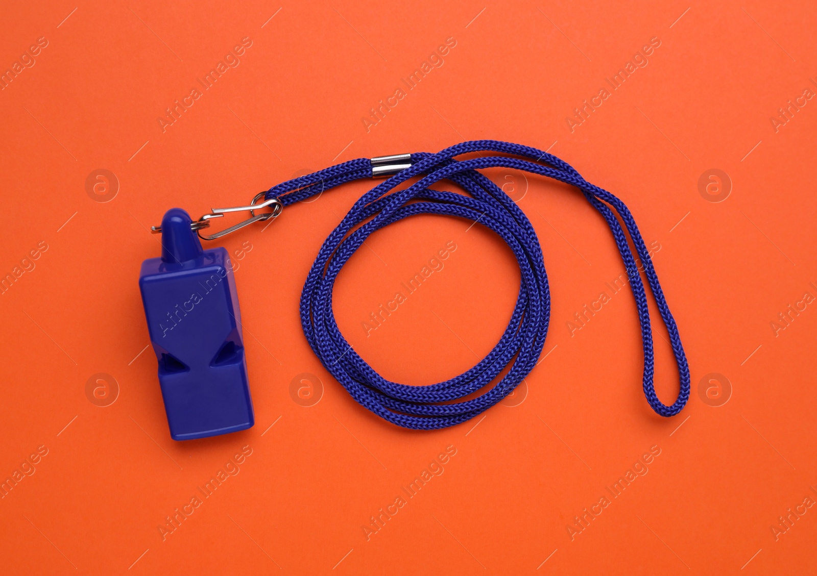 Photo of One blue whistle with cord on orange background, top view