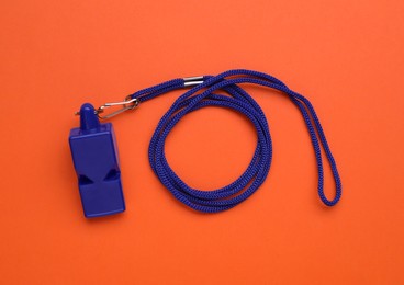 One blue whistle with cord on orange background, top view