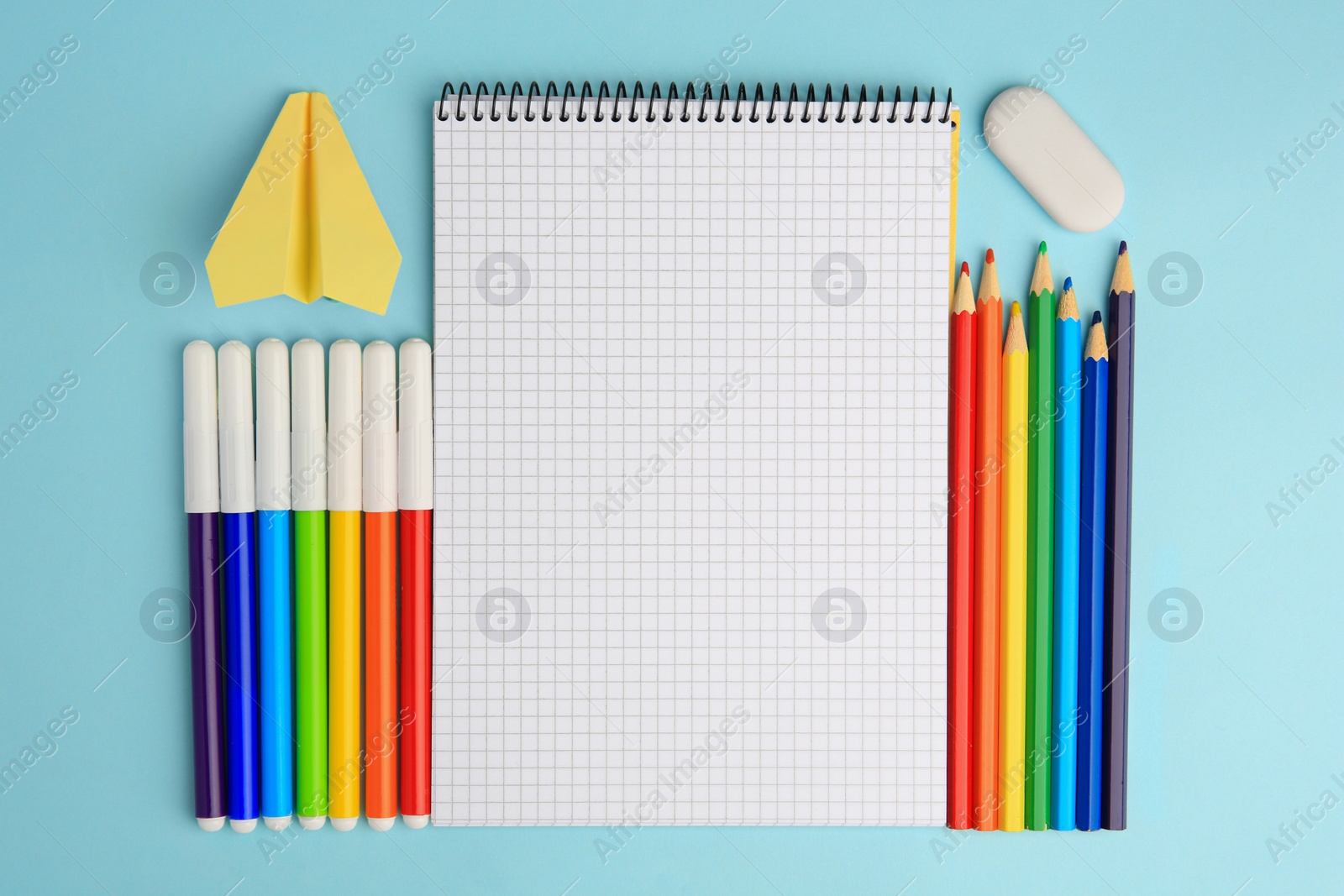 Photo of Flat lay composition with open notebook and other school stationery on light blue background, space for text. Back to school