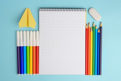 Photo of Flat lay composition with open notebook and other school stationery on light blue background, space for text. Back to school