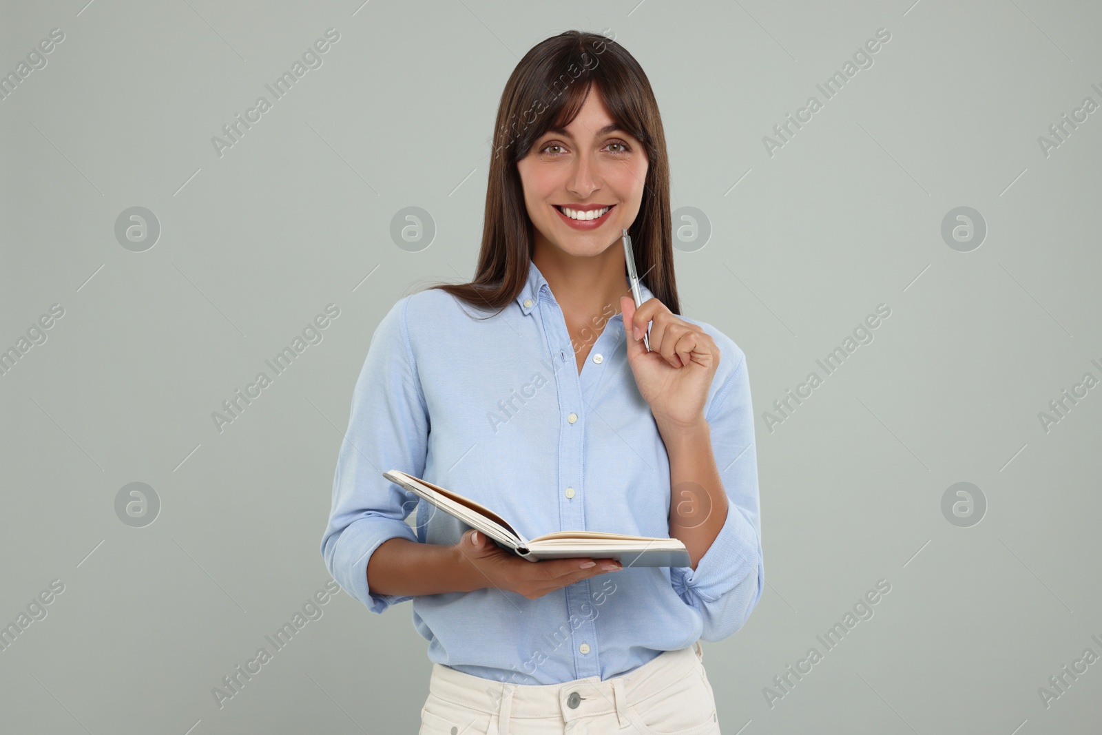 Photo of Happy secretary with notebook and pen on light grey background