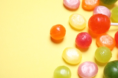 Photo of Many different hard candies on yellow background, closeup. Space for text