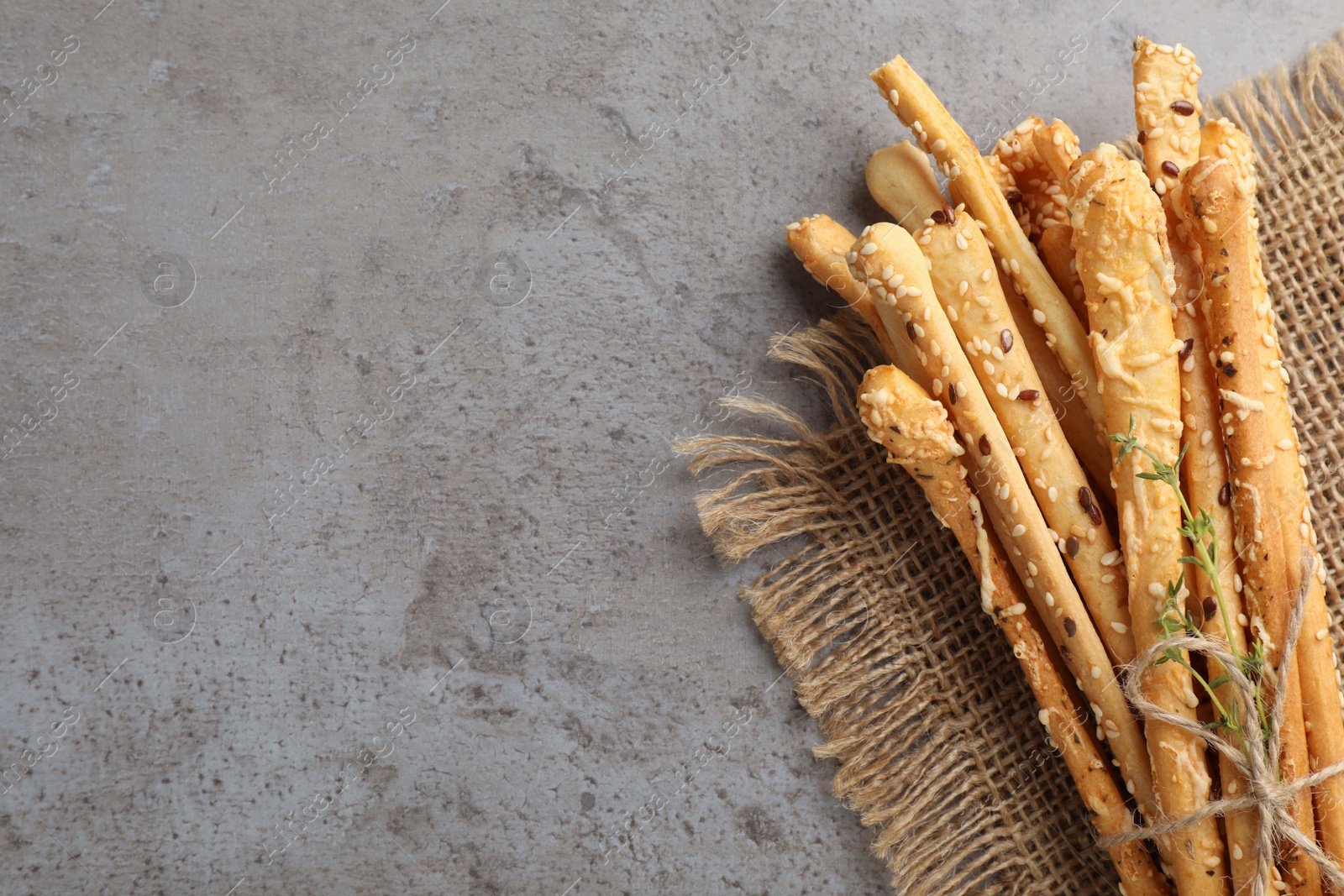 Photo of Delicious grissini sticks with thyme on grey table, top view. Space for text