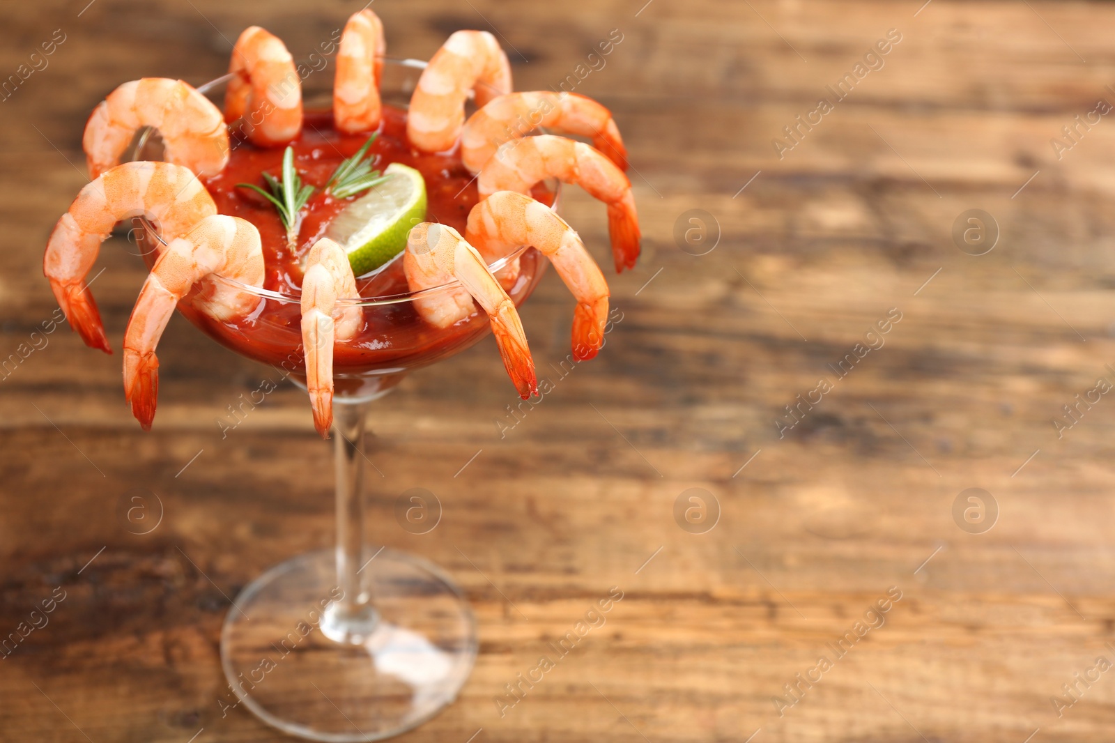 Photo of Shrimp cocktail with tomato sauce on wooden table. Space for text