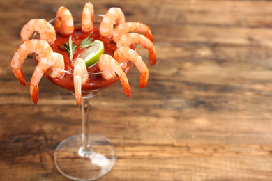 Photo of Shrimp cocktail with tomato sauce on wooden table. Space for text