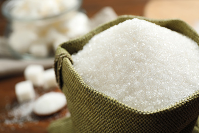 Photo of Granulated sugar in sack on table, closeup