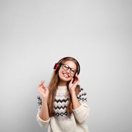 Photo of Young woman listening to music with headphones on grey background