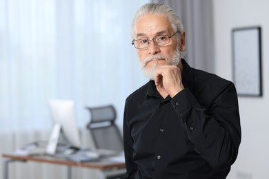 Photo of Portrait of handsome senior man in black shirt and eyeglasses at home. Space for text