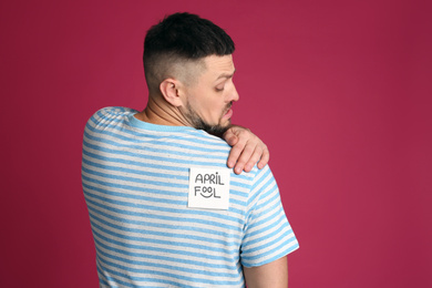Photo of Man with APRIL FOOL sticker on back against pink background