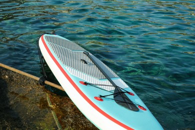 Photo of One SUP board with paddle on sea shore