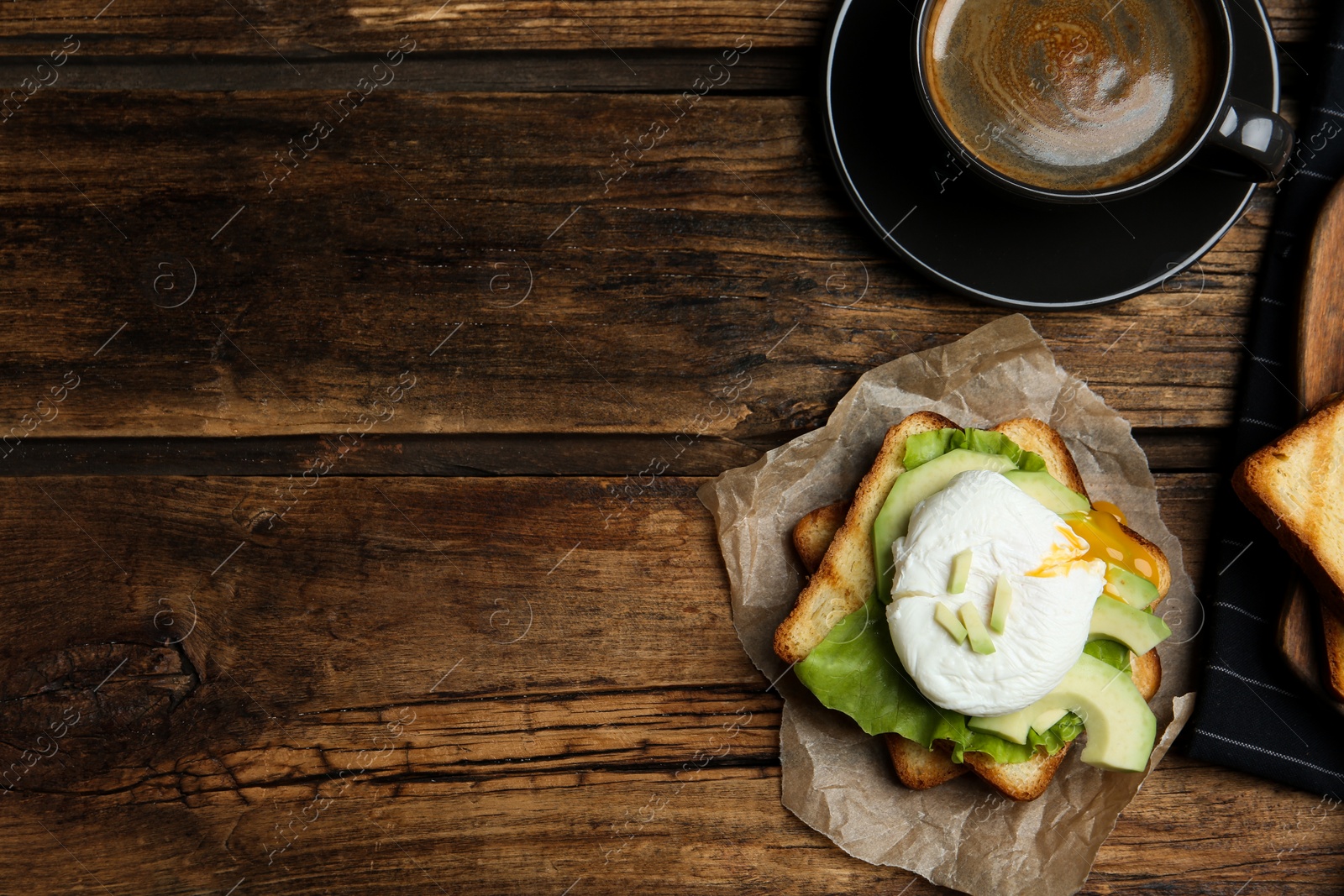 Photo of Delicious poached egg sandwich served on wooden table, flat lay. Space for text