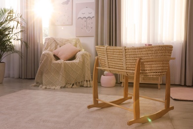 Photo of Beautiful cradle and armchair in baby room. Interior design