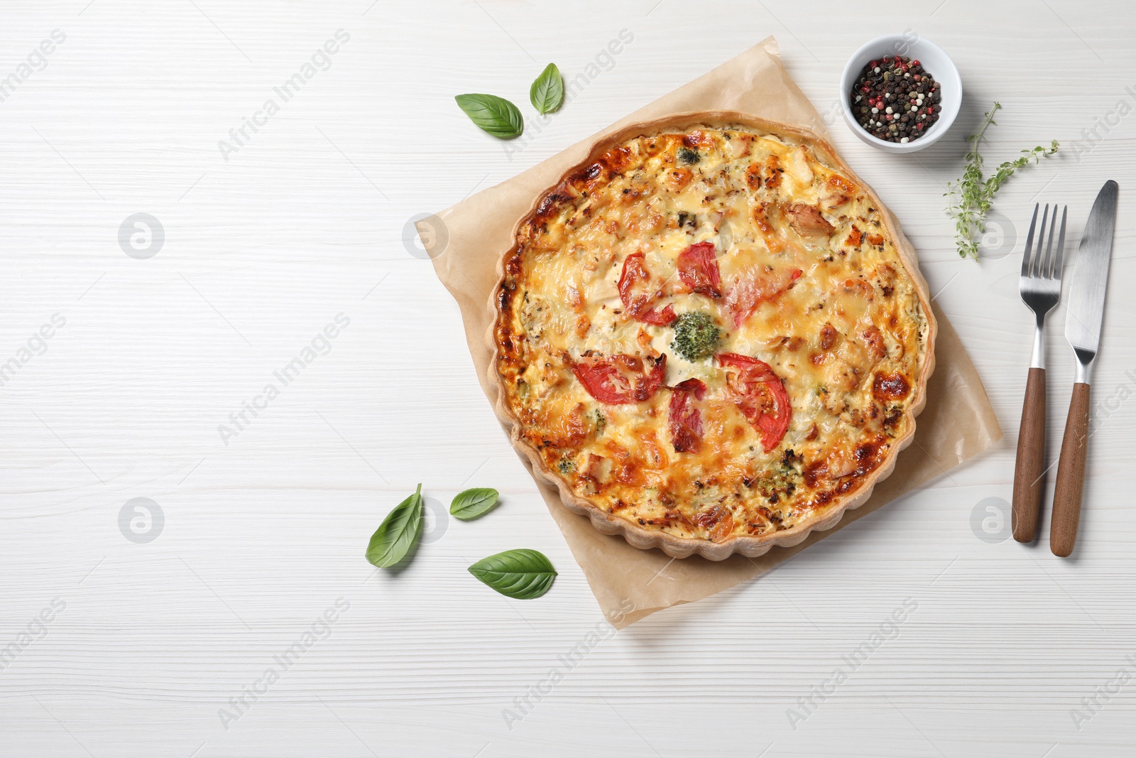 Photo of Tasty cheese quiche and cutlery on white wooden table, flat lay