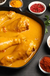 Photo of Tasty chicken curry and ingredients on black table