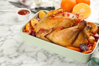 Roasted chicken with oranges, pomegranate and vegetables on white marble table