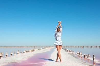 Beautiful woman posing near pink lake on summer day