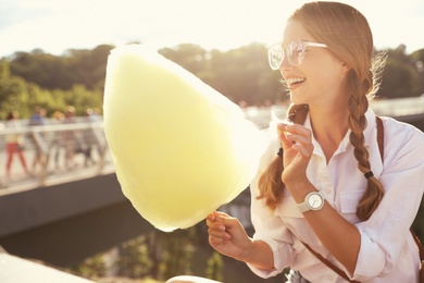 Young woman with cotton candy outdoors on sunny day