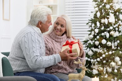 Happy mature couple with gift box at home. Christmas celebration