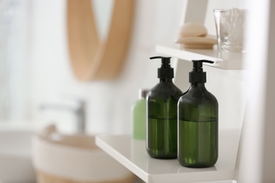 Photo of Green soap dispensers on white shelving unit in bathroom. Space for text