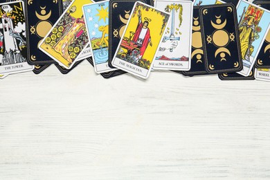Photo of Tarot cards on white wooden table, top view. Space for text.