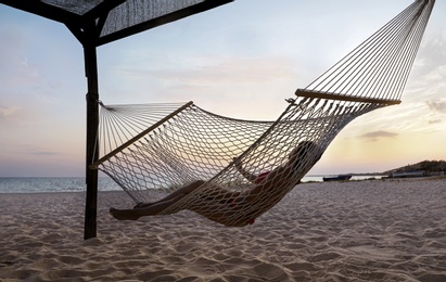 Young woman relaxing in hammock on beach