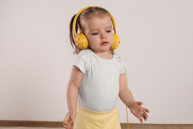 Photo of Cute little girl with headphones listening to music at home