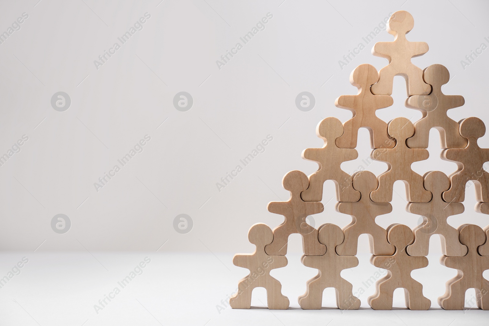 Photo of Recruitment process, job competition concept. Pyramid of wooden human figures with noticeable one on top as prime applicant on white table, space for text