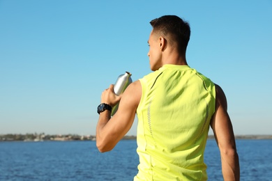Photo of Young sporty man with water bottle outdoors on sunny day. Space for text